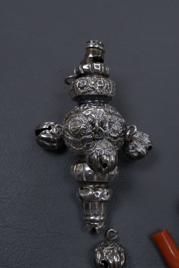 A late Victorian silver child's rattle, with four (ex five) bells and damaged coral teether, Colen Hewer, Cheshire, Birmingham, 1890, 78mm without the coral.